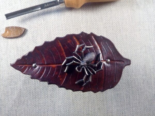 Przód skórzanej spinki do włosów z pająkiem.