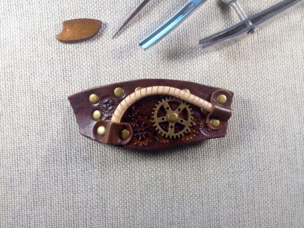 Skórzana spinka do włosów w stylu steampunkowym. Po prawej stronie przynitowane jest metalowe kółko zębate.