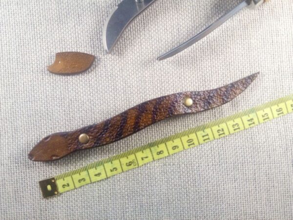 Skórzana spinka do włosów w wersji 1 w kształcie węża. Obok miara krawiecka.