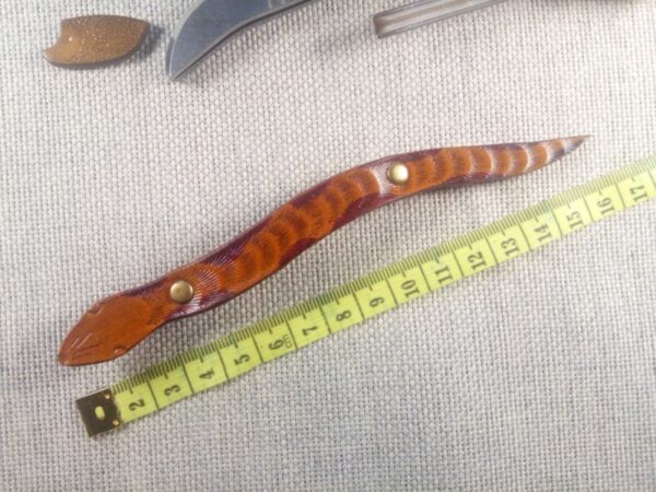 Skórzana spinka do włosów w kształcie węża w wersji 2. Obok miara krawiecka.