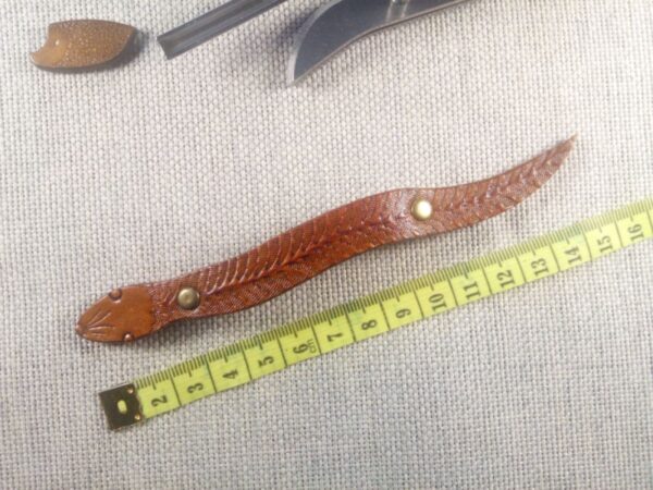 Spinka do włosów ze skóry naturalnej bydlęcej w kształcie węża w wersji 3 z miarą krawiecką obok.