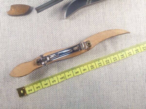 Tył skórzanej spinki do włosów z widokiem na klamrę i miarę.