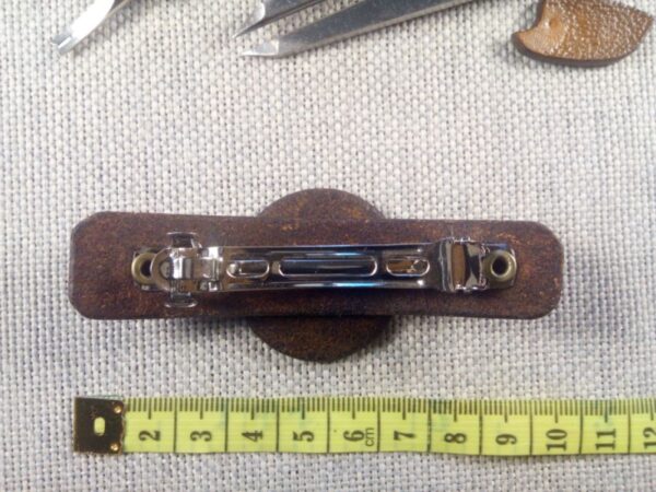 Widok od tyłu na klamrę na skórzaną spinkę do włosów i miarę krawiecką.