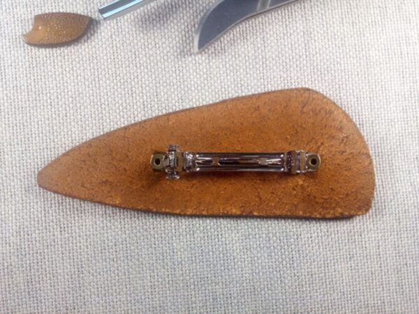 Tył skórzanej spinki do włosów z wytłoczoną głową wilka.