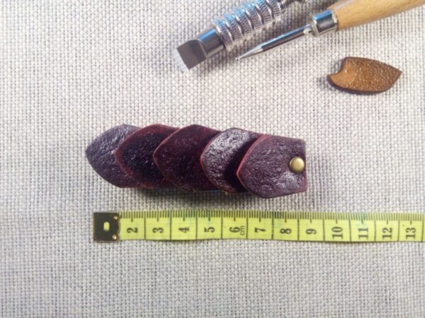 Widok do przodu - skórzana spinka do włosów wykonana z pięciu łusek smoka z miara krawiecką