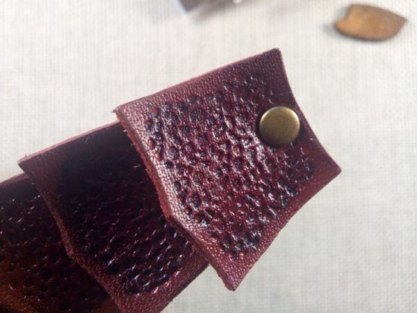 Zbliżenie na skórzaną spinkę do włosów wkolorze bordowym.