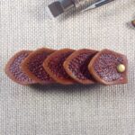 Widok do przodu - skórzana spinka do włosów wykonana z pięciu łusek smoka w kolorze brązowym.