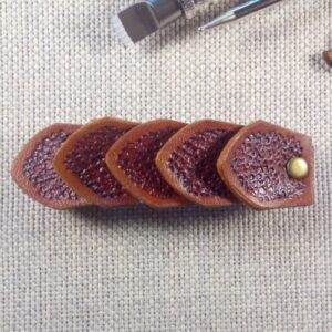 Widok do przodu - skórzana spinka do włosów wykonana z pięciu łusek smoka w kolorze brązowym.