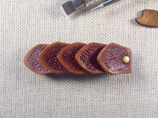 Widok do przodu - skórzana spinka do włosów wykonana z pięciu łusek smoka w kolorze brązowym.