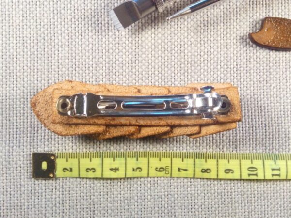 Skórzana spinka do włosów z miarą krawiecką.