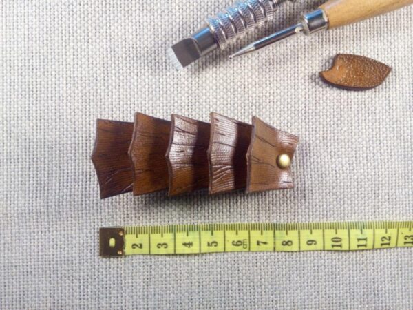 Widok do przodu - skórzana spinka do włosów wykonana z pięciu łusek smoka z miara krawiecką