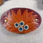 Skórzana spinka do włosów z kwiatem i kryształkami. Widok od przodu.