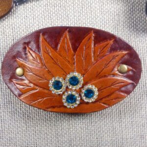Skórzana spinka do włosów z kwiatem i kryształkami. Widok od przodu.