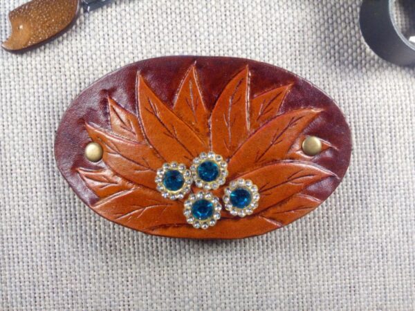 Skórzana spinka do włosów z kwiatem i kryształkami. Widok od przodu.