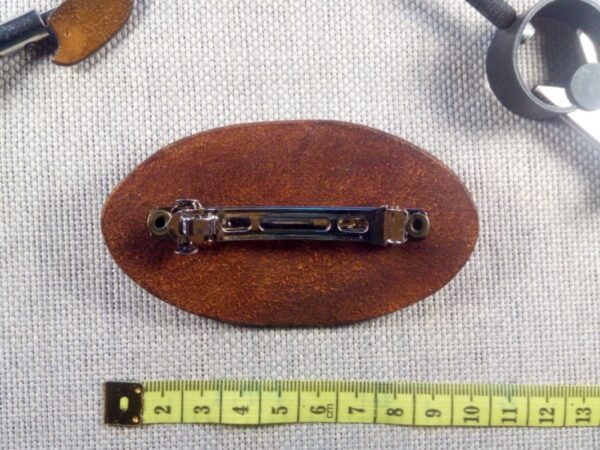 Skórzana spinka do włosów z kwiatem i kryształkiem. Widok od tyłu z miarą krawiecką.