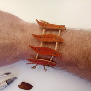 Skórzana bransoletka z listkami na ręce.