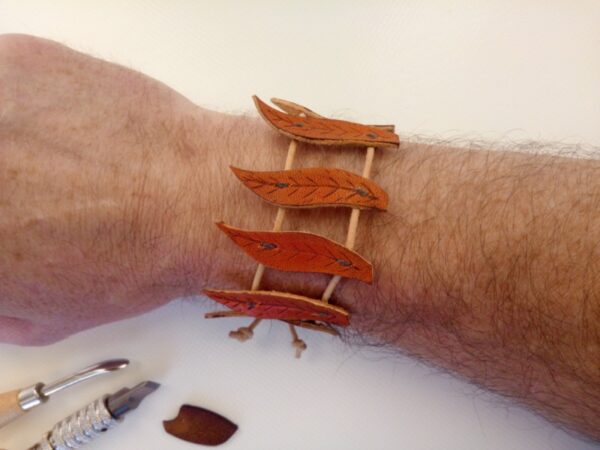 Skórzana bransoletka z listkami na ręce.